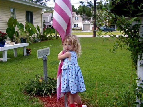 Little Munchkin hugging our neighbor's flag.
